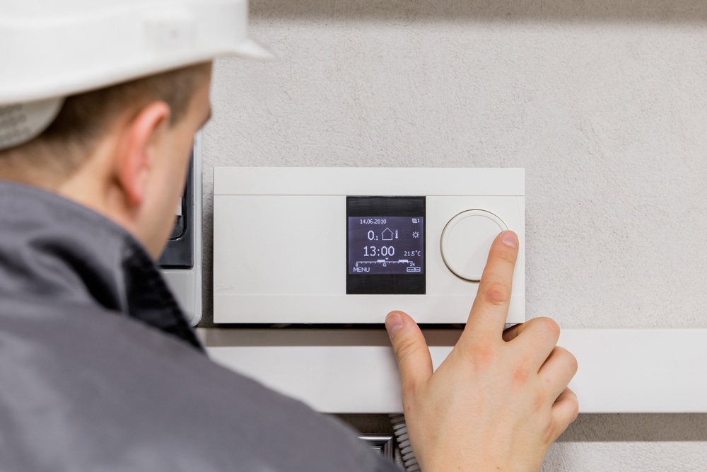 man changing air conditioning thermostat